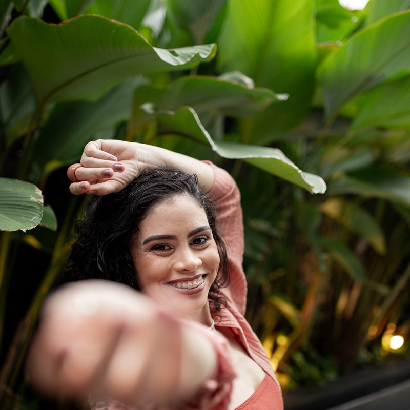 Mulher sorrindo em jardim, gesto de convite