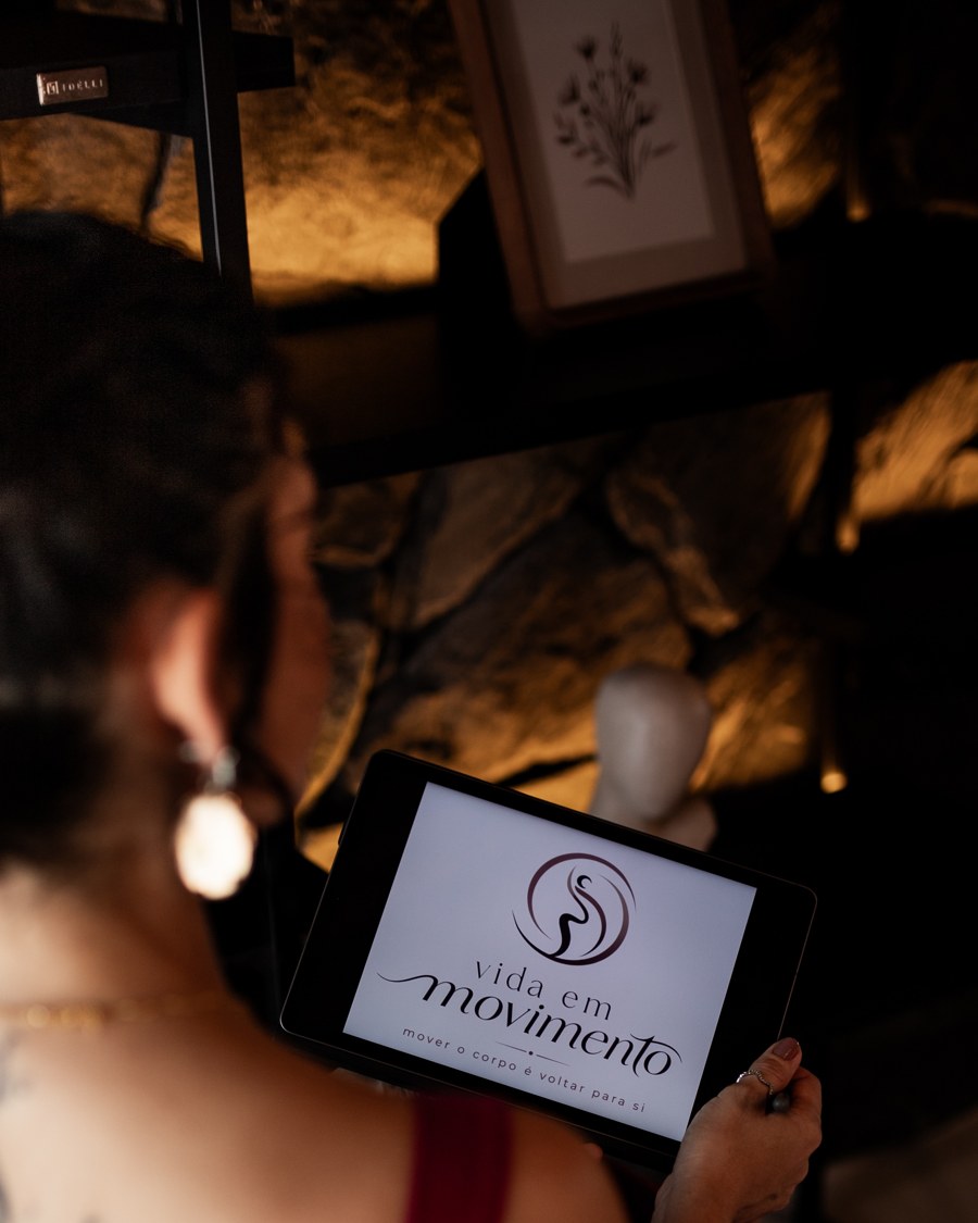 Elisa Soares segurando um tablet com o logo do Vida em Movimento na tela